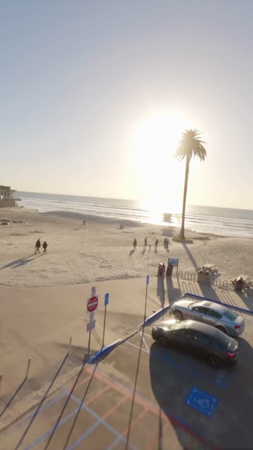 Vertical FPV drone video over Moonlight Beach in Encinitas California with ocean waves shoreline sand and beach activity on a sunny afternoon