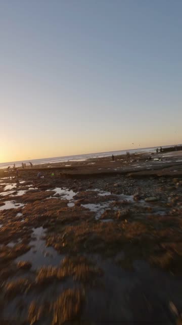 The beach, the ocean and open country at Swamis, with people walking.