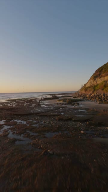Low aerial view of the beach, the ocean and the cliffs at Swamis.