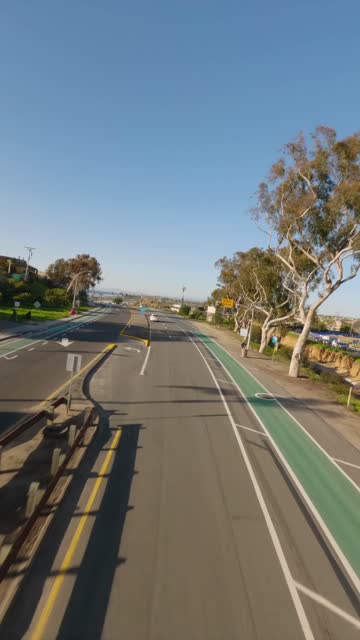 Low aerial view of a residential street, traffic and open country at Downtown Encinitas.