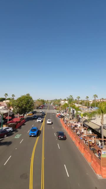 Low aerial view of the downtown streets, palm trees and homes at Downtown Encinitas, with people walking.