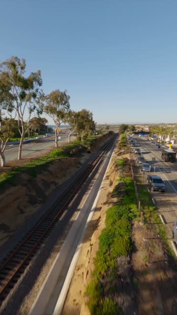 Low aerial view of a residential street, traffic and open country at Downtown Encinitas.