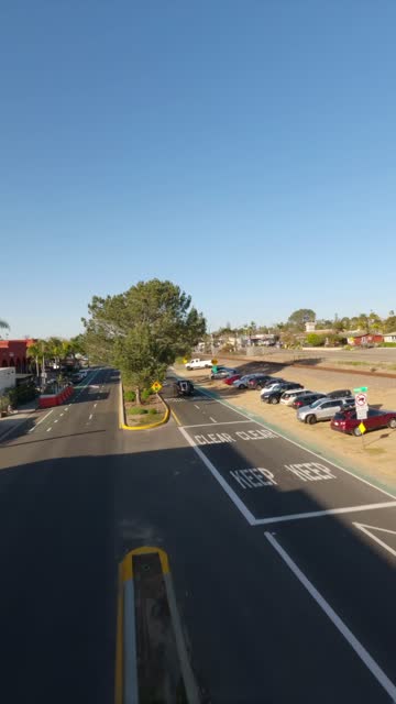 Low aerial view of a residential street, palm trees and traffic at Downtown Encinitas.