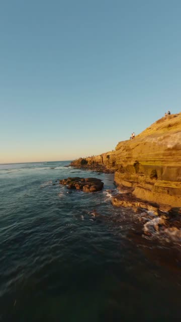 Low aerial view of the cliffs, the surf and the ocean at Sunset Cliffs.