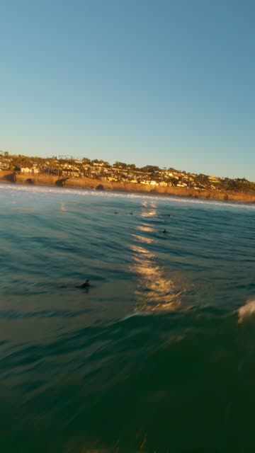 View from the water of the beach, the surf and the ocean at Sunset Cliffs, with surfers out.