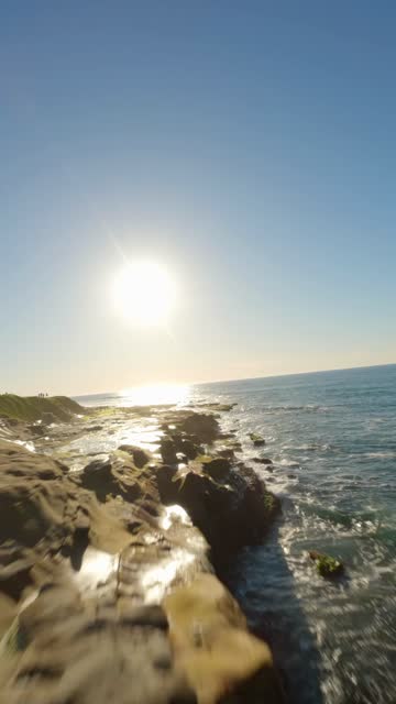 Low aerial view of the cliffs, the surf and the ocean at La Jolla Cove.