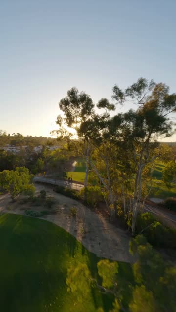 Low aerial view of a park, homes and open country at Covenant, with people walking.