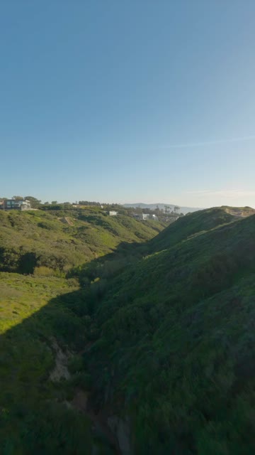 Low aerial view of the cliffs, homes and open country at Black’s Beach.