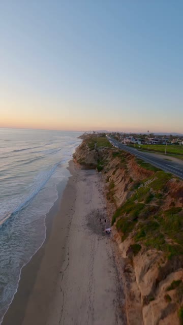 Aerial view of the cliffs, the surf and the ocean in Carlsbad, with people walking.