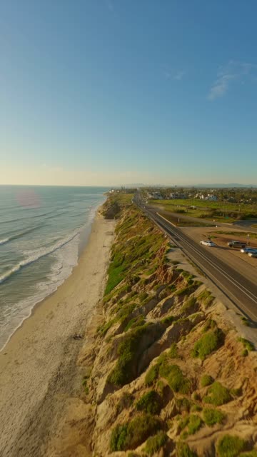 Aerial view of the cliffs, the surf and the ocean in Carlsbad, with people walking.