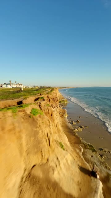 Low aerial view of the cliffs, the ocean and homes in Carlsbad.
