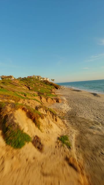 Low aerial view of the cliffs, the ocean and homes in Carlsbad.