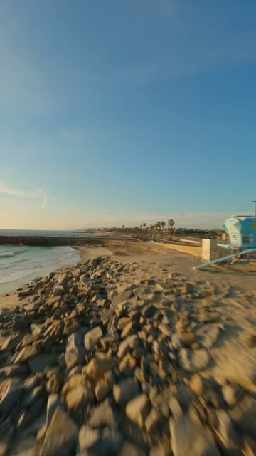 Low aerial view of the beach, the surf and palm trees in Carlsbad.