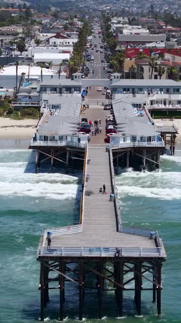 Aerial view of the beach, the surf and the pier in Pacific Beach, with people walking.
