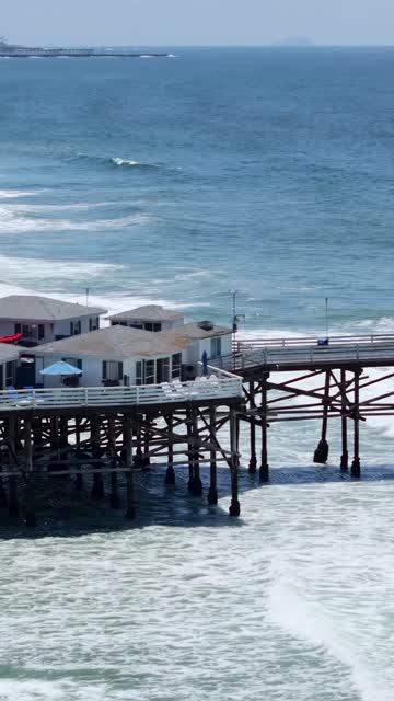 Low aerial view of the beach, the surf and the pier in Pacific Beach.