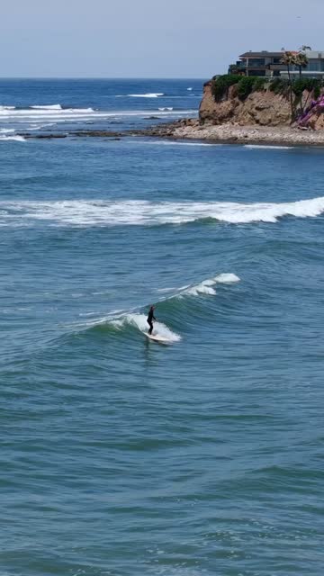 Low aerial view of the beach, the surf and the ocean at Tourmaline, with surfers out.