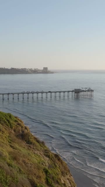 Low aerial view of the cliffs, the pier and the ocean at La Jolla Shores.