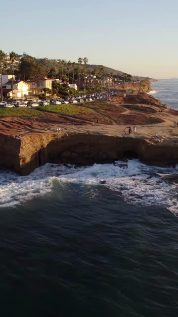 Aerial view of the cliffs, the surf and palm trees at Sunset Cliffs, with people walking.