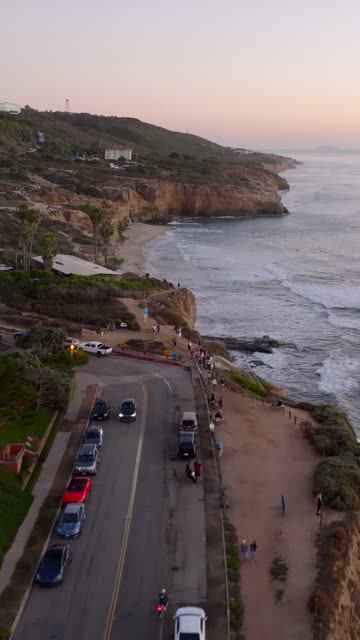 Aerial view of the cliffs, the surf and palm trees at Sunset Cliffs, with people walking.