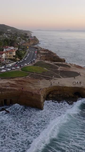 Aerial view of the cliffs, the surf and the ocean at Sunset Cliffs, with a crowd gathered.