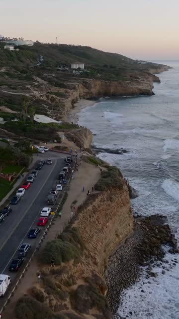 Aerial view of the cliffs, the surf and the ocean at Sunset Cliffs, with people walking.