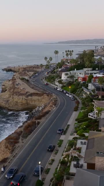 Aerial view of the cliffs, the surf and palm trees at Sunset Cliffs, with people walking.