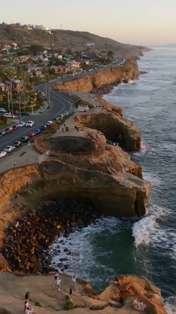 Aerial view of the cliffs, the surf and palm trees at Sunset Cliffs, with people walking.