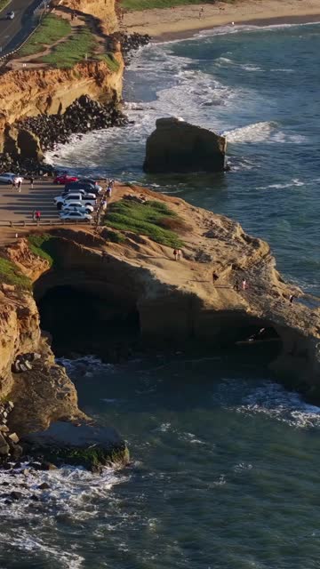 Aerial view of the cliffs, the surf and the ocean at Sunset Cliffs, with people walking.