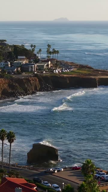 Vertical drone video of a vibrant sunset at Sunset Cliffs Natural Park in San Diego California featuring coastal bluffs rolling waves and people watching the sunset | Vertical Drone Video – 37