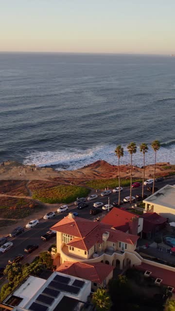Aerial view of the cliffs, the surf and palm trees at Sunset Cliffs, with people walking.