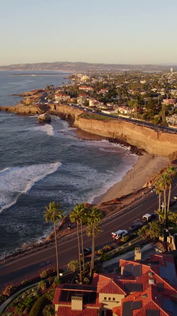 Aerial view of the cliffs, the surf and palm trees at Sunset Cliffs, with people walking.