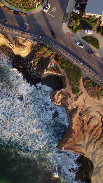 Aerial view of the cliffs, the surf and the ocean at Sunset Cliffs, with people walking.
