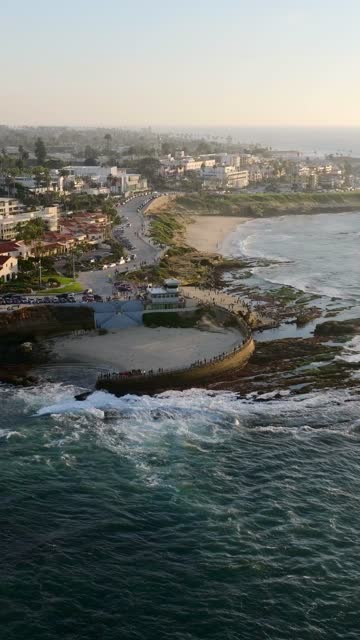 Aerial view of the beach, the surf and the ocean at La Jolla Cove, with a crowd gathered.