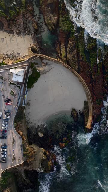 Aerial view of the beach, the surf and the ocean at La Jolla Cove, with a crowd gathered.