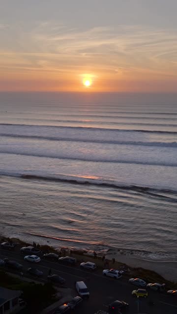 Aerial view of the cliffs, the surf and the ocean at Sunset Cliffs, with a crowd gathered.