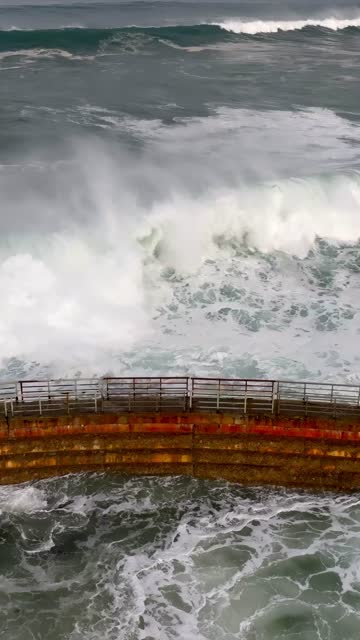 Low aerial view of the cliffs, the surf and the ocean at La Jolla Cove.