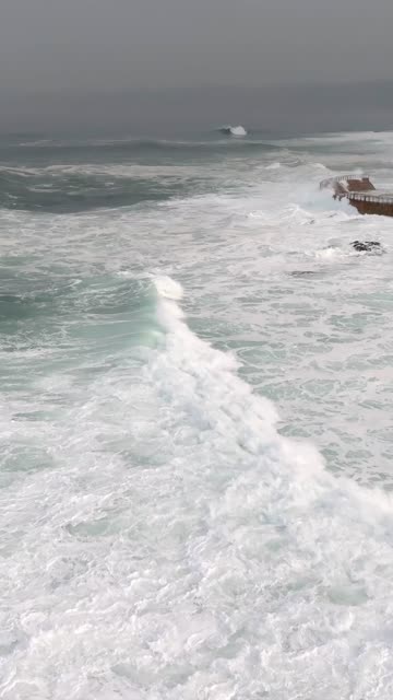 Low aerial view of the cliffs, the surf and the ocean at La Jolla Cove.