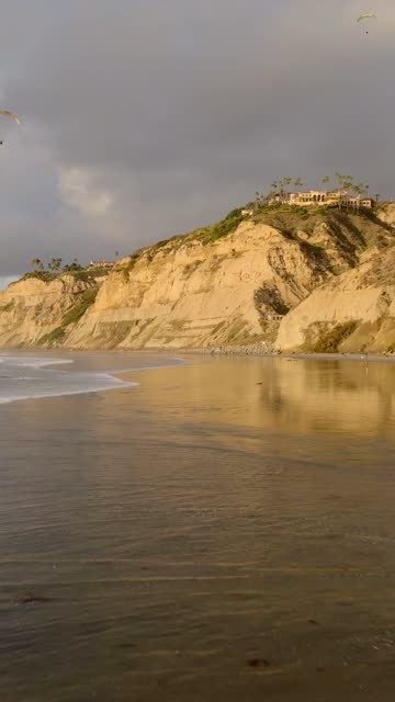 Low aerial view of the beach, the surf and the ocean at Black’s Beach.