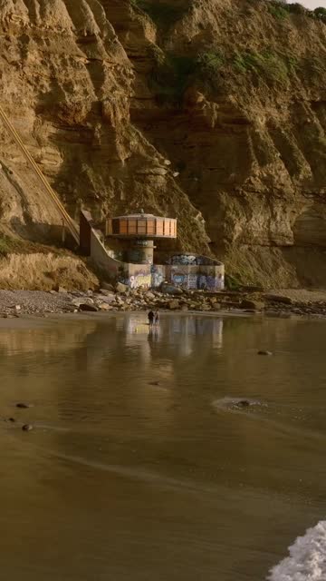 The cliffs, the ocean and the beach at Black’s Beach, with people walking.
