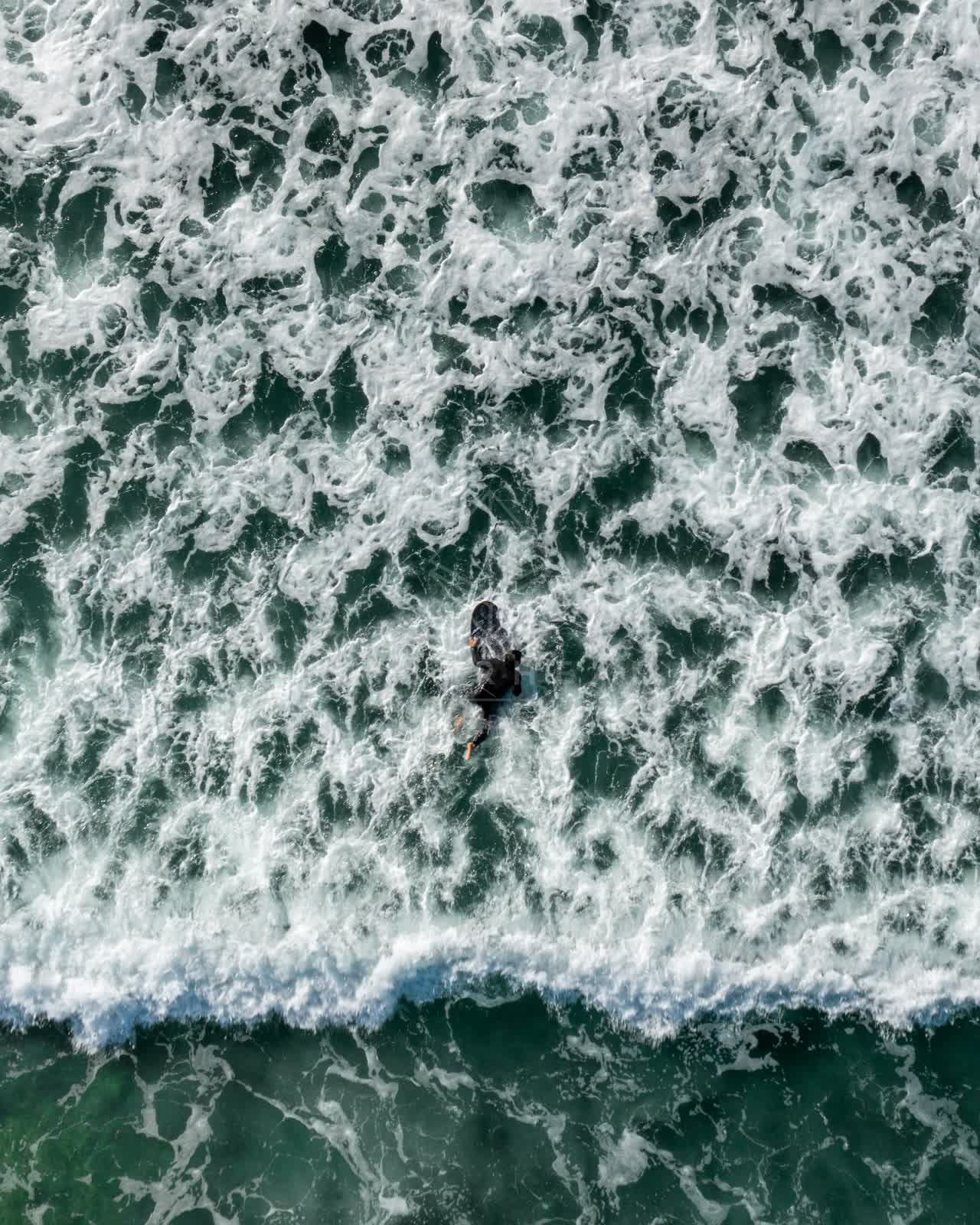 Aerial view of the beach, the surf and the ocean in Cardiff, with surfers out.