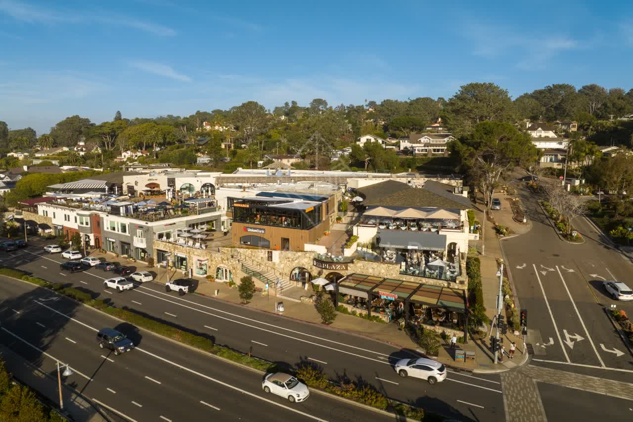 Low aerial view of the downtown streets, homes and the buildings in Del Mar, with people eating outside.