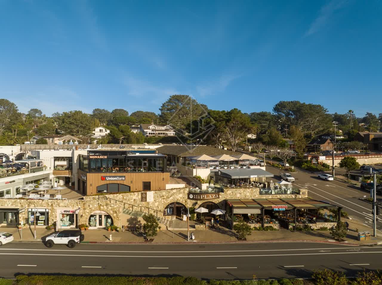 Low aerial view of the downtown streets, homes and the buildings in Del Mar, with people eating outside.