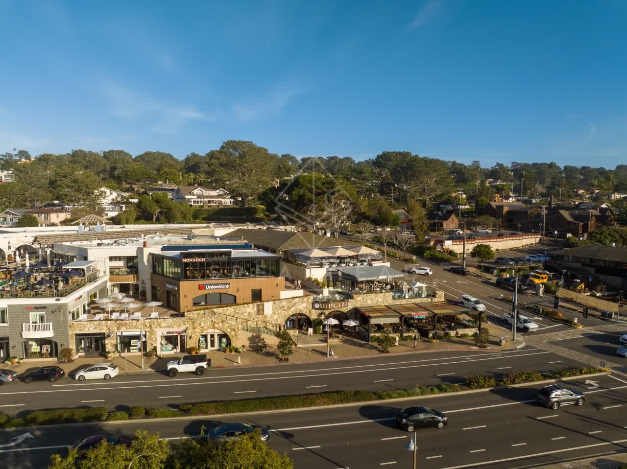 Low aerial view of the downtown streets, homes and the buildings in Del Mar, with people eating outside.