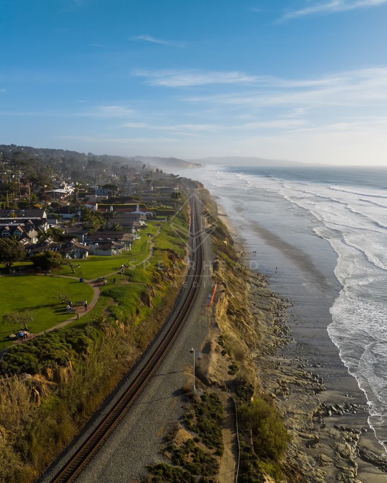 Aerial view of the cliffs, the surf and the ocean in Del Mar, with people walking.