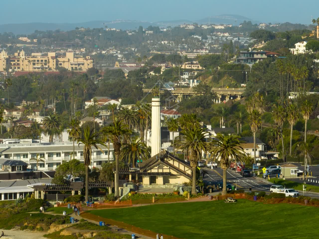 Aerial view of a residential street, the bridge and palm trees in Del Mar, with people walking.