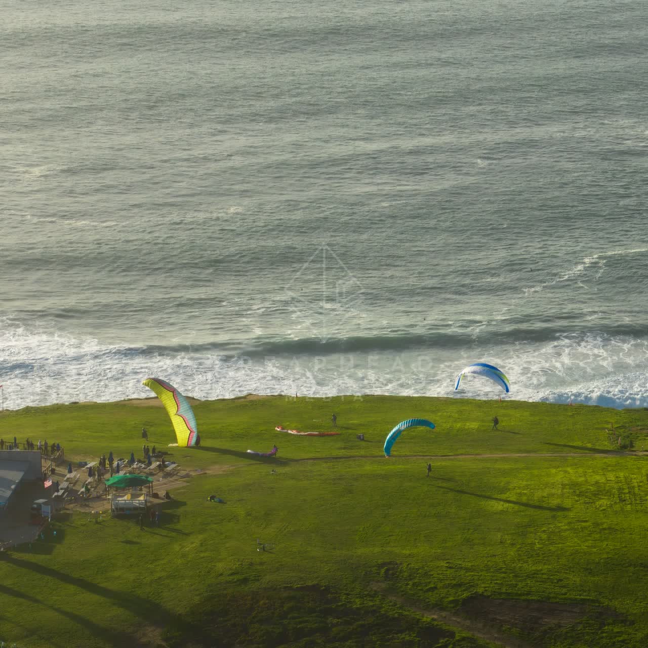 Aerial view of the cliffs, the surf and the ocean at Torrey Pines, with a crowd gathered.
