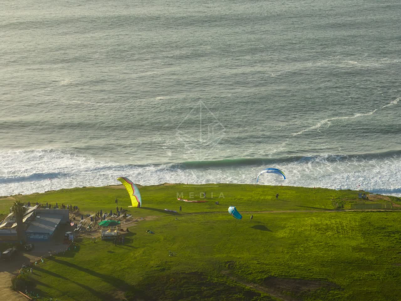 Aerial view of the cliffs, the surf and the ocean at Torrey Pines, with a crowd gathered.