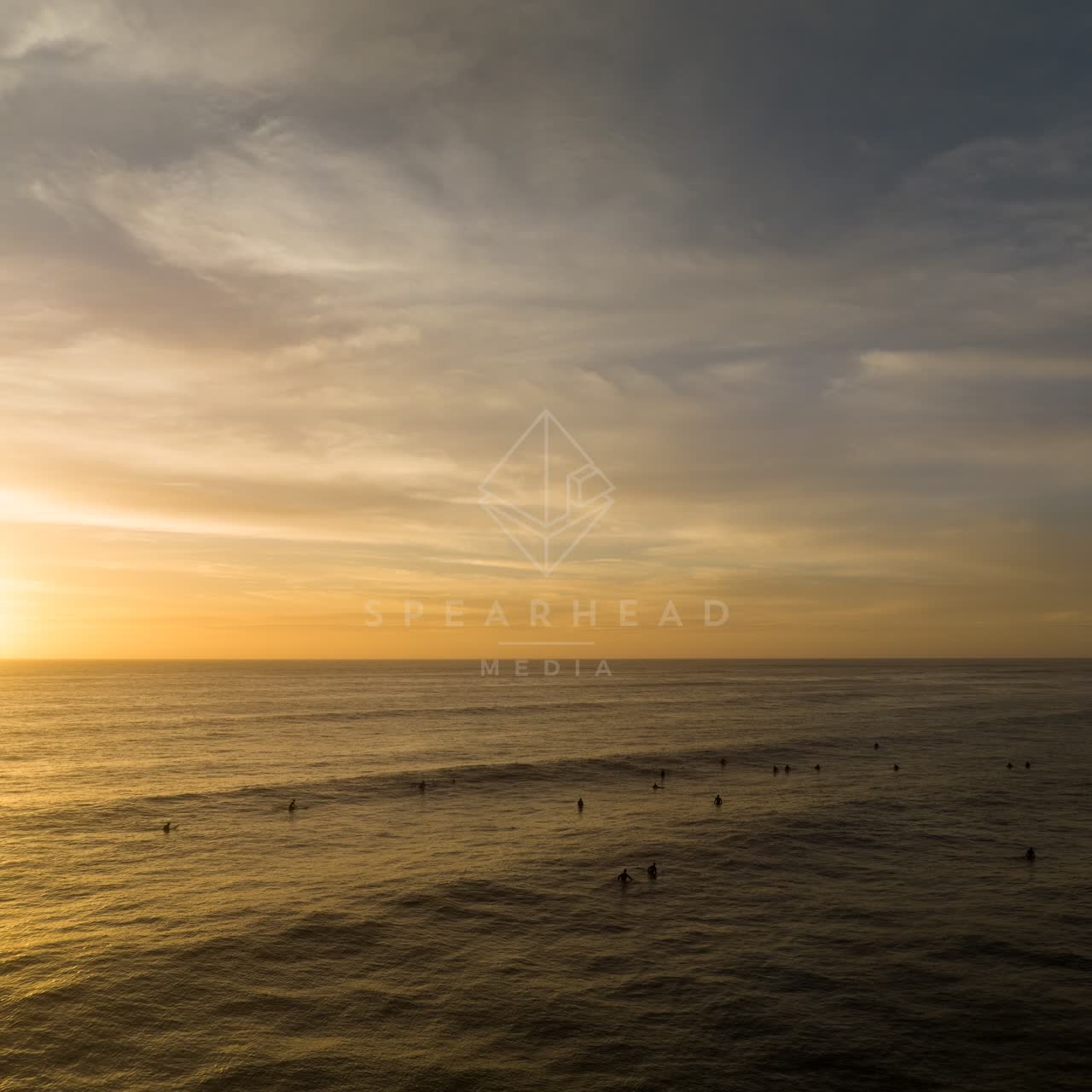 Low aerial view of the beach, the ocean and open country in Pacific Beach, with surfers out.