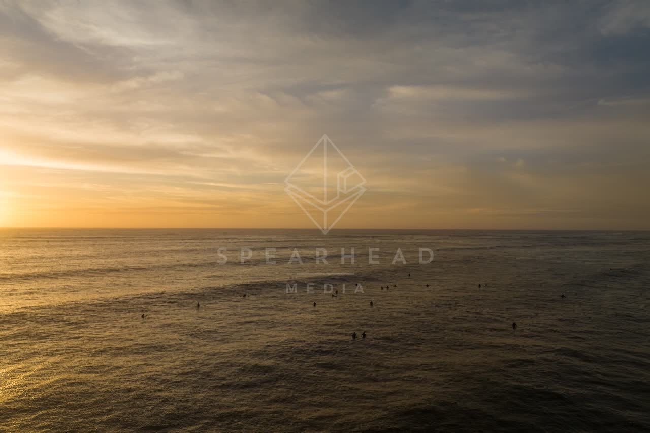 Low aerial view of the beach, the surf and the ocean in Pacific Beach, with surfers out.