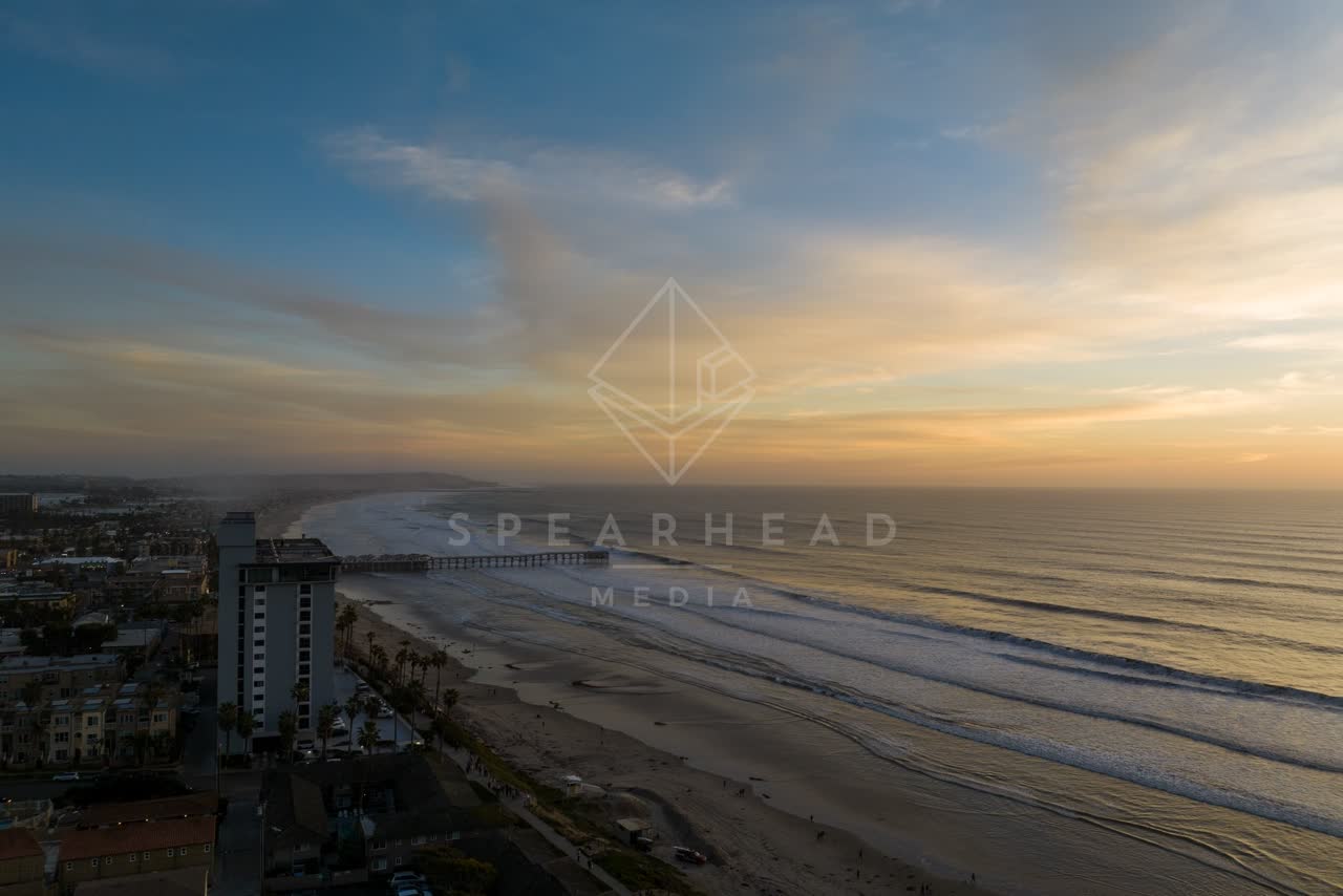 Aerial view of the beach, the surf and the pier in Pacific Beach, with people walking.